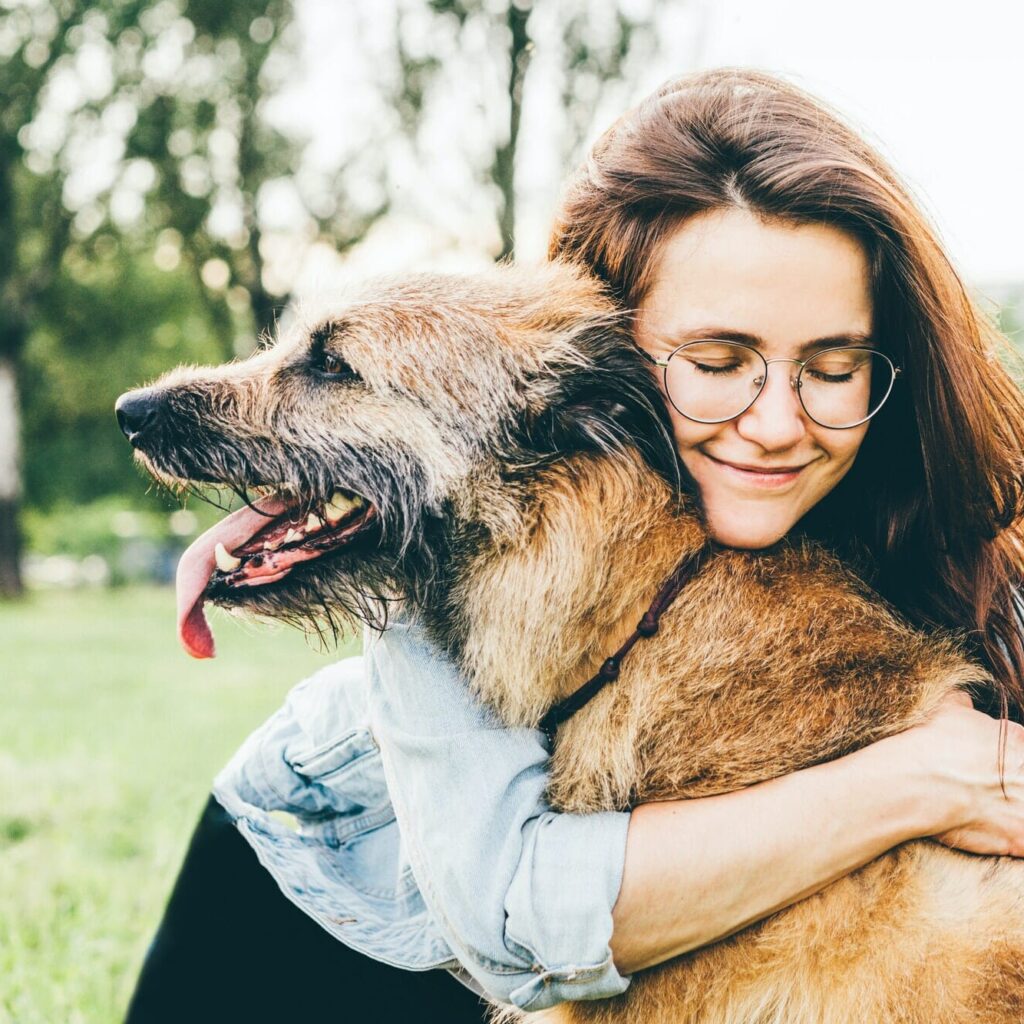Women hugging dog in the summer park.